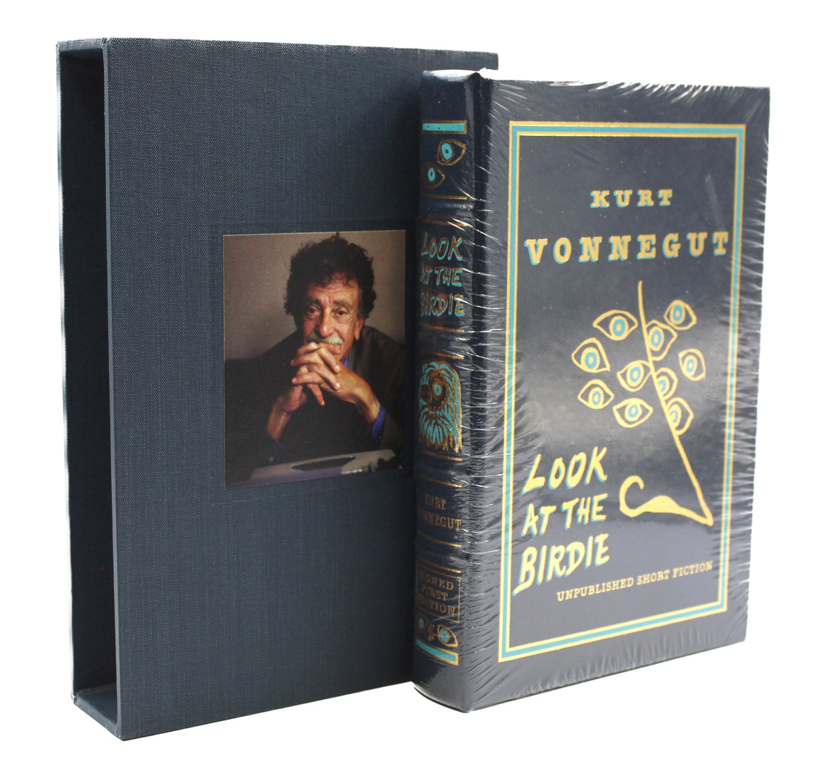 The novel and it's slipcase, standing slightly staggered next to eachother. The slipcase is placed behind the novel to the left, featuring a color portrait photo of Kurt Vonnegut. The novel is to the right, still shrinkwrapped. 