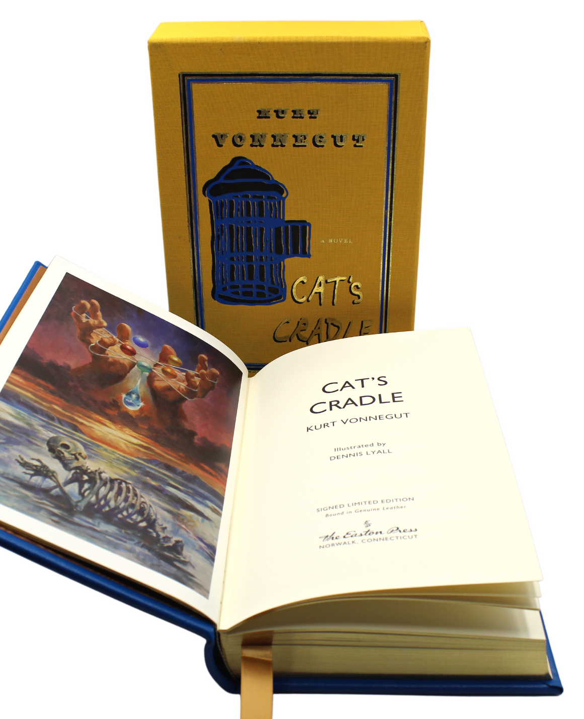 The novel and slipcase pictured together, with the novel set in front of the slipcase. The novel is bound in blue leather, with the cover art printed in yellow, black, and gold. "Kurt Vonnegut" is printed top center, featuring a  yellow and black quirky illustration of an open birdcage in the center. The words "a novel" appear to be coming out of the opened cage door, with the title "Cat's Cradle" printed underneath in a gold and black type.